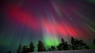 northern lights in sky appear as red and green ribbons and pillars of light