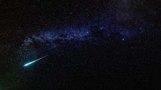 a bright meteor streaks through a star-studded sky