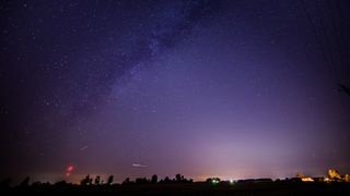 Draconid meteors streak across the night sky. The Milky Way can also be seen stretching across the star-studded sky.